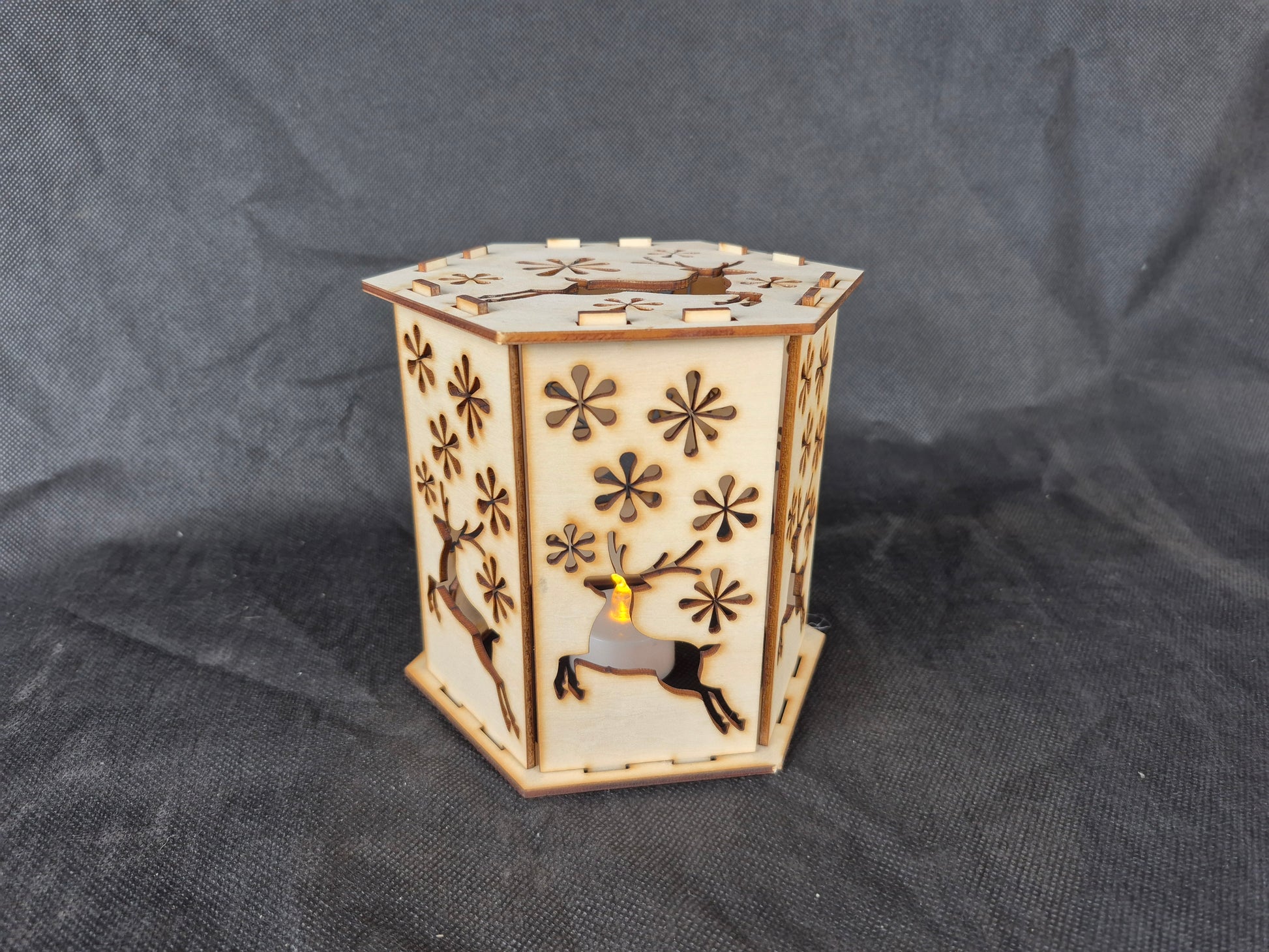 Wooden silhouette Christmas lamp with laser cut festive scene creating shadow effects