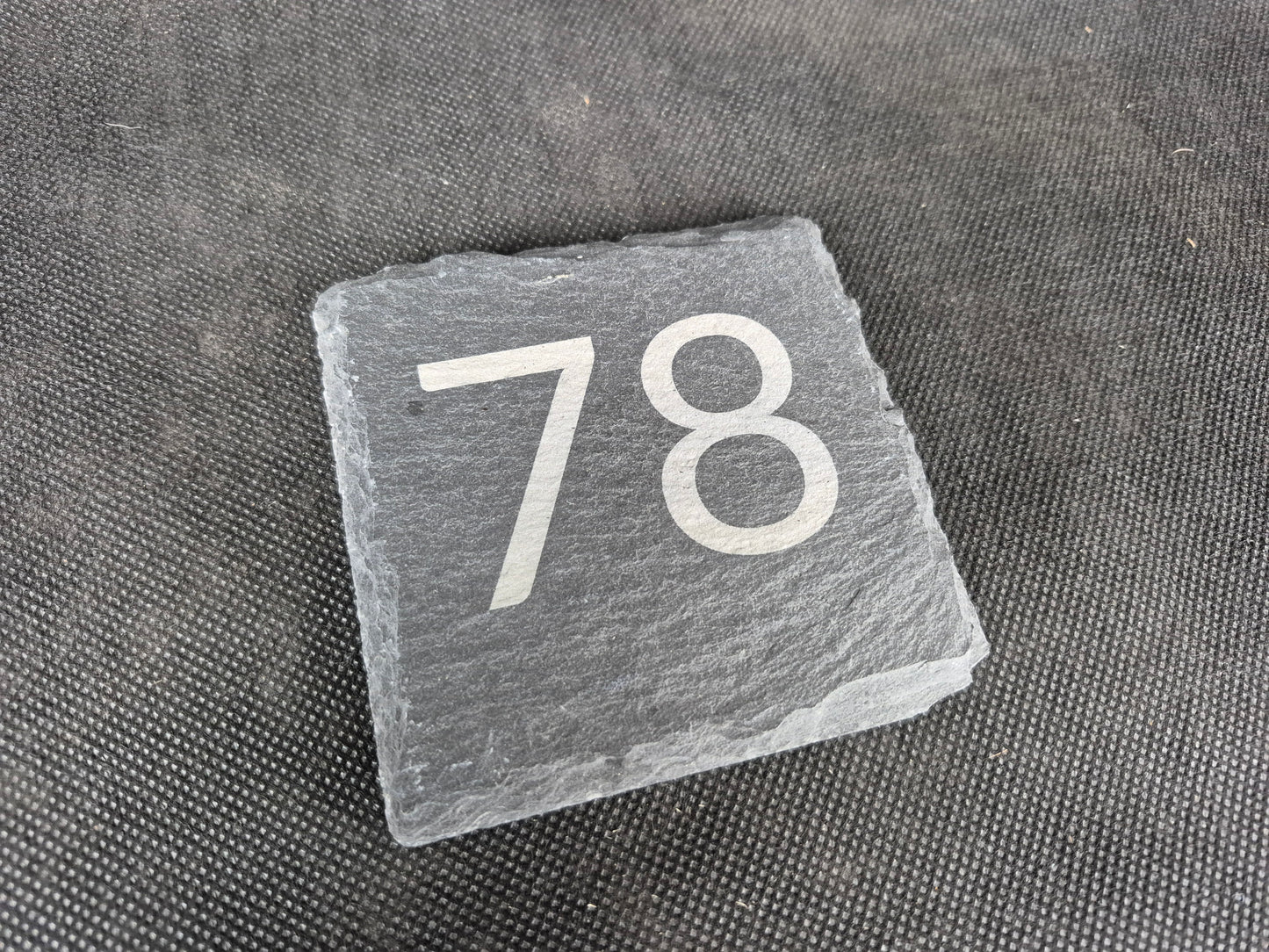 Natural black slate drink coaster with custom laser engraved design and protective feet