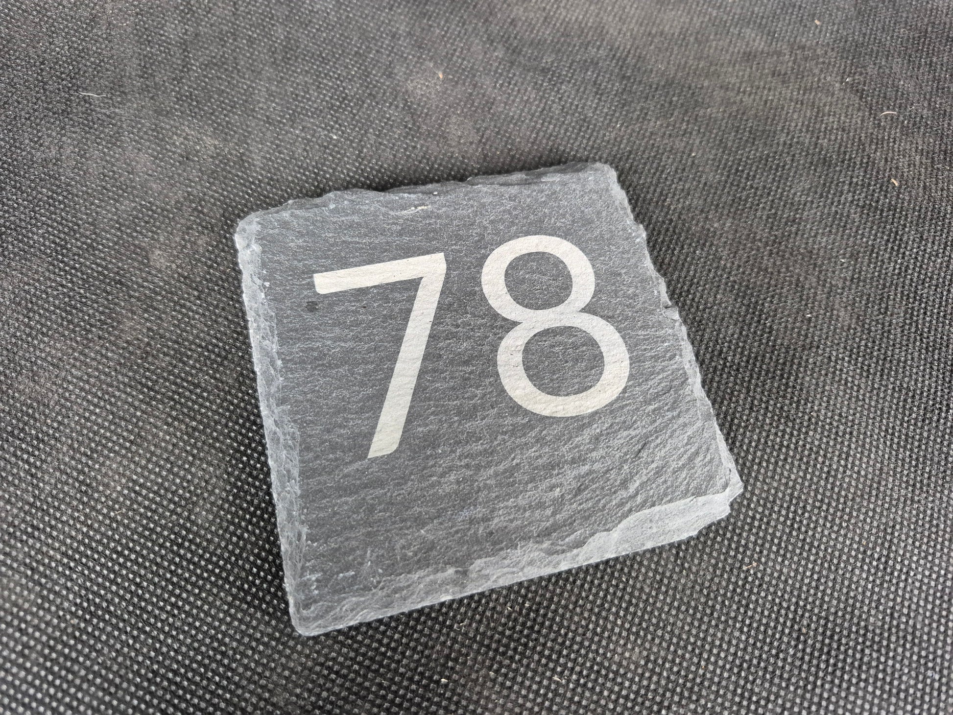 Natural black slate drink coaster with custom laser engraved design and protective feet