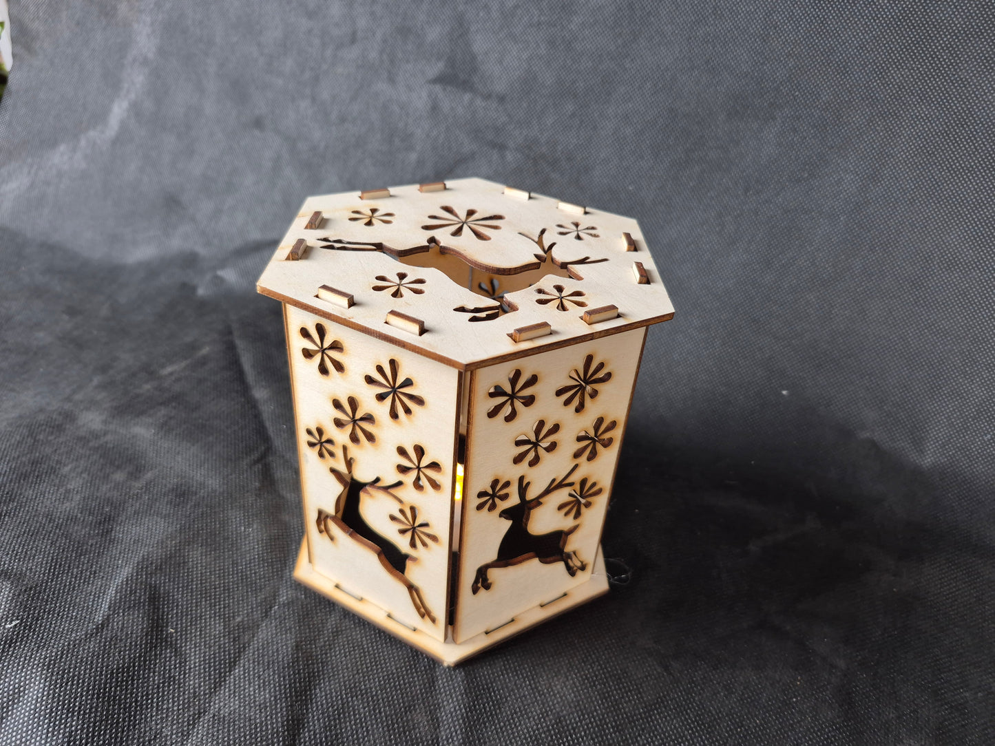 Wooden silhouette Christmas lamp with laser cut festive scene creating shadow effects
