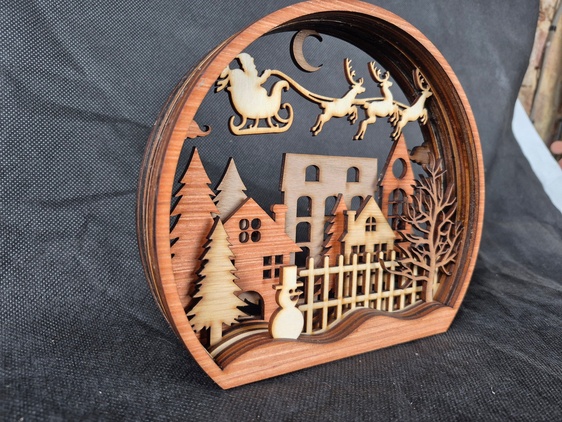 Multi-layered wooden Christmas display with intricate laser cut winter scene and stable base