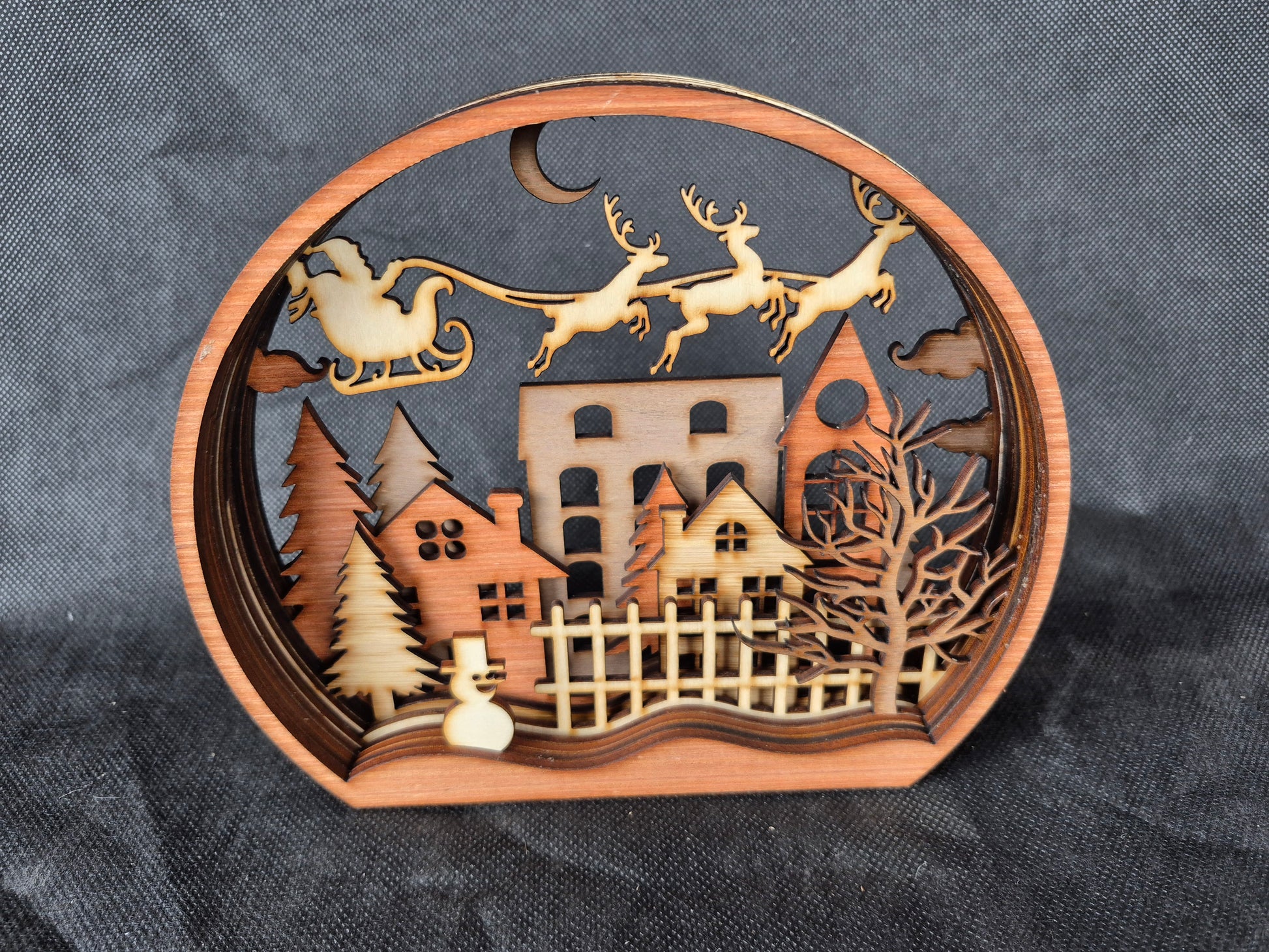 Multi-layered wooden Christmas display with intricate laser cut winter scene and stable base