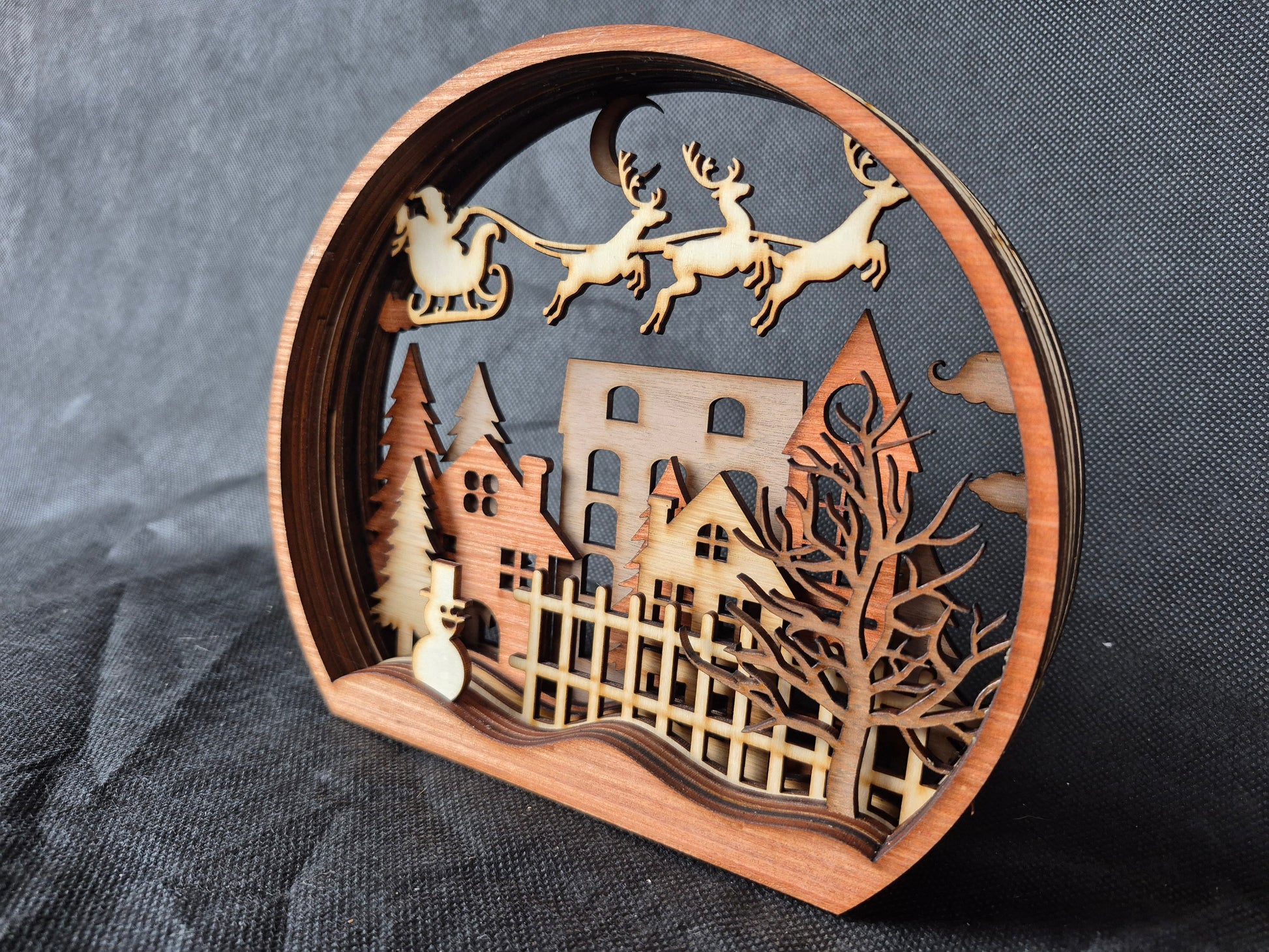 Multi-layered wooden Christmas display with intricate laser cut winter scene and stable base